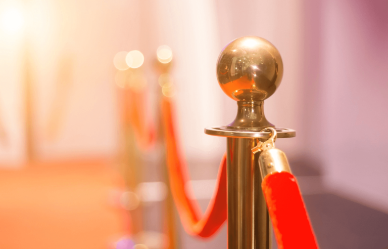 Golden stanchion with red velvet rope in a softly lit setting.