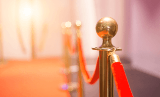 Golden stanchions with red velvet ropes in a softly lit corridor.
