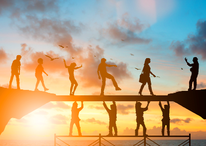 Silhouettes of four people dancing on a dock at sunset with their reflections in the water.