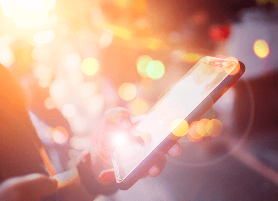 Person using a smartphone with glowing bokeh lights in the background.